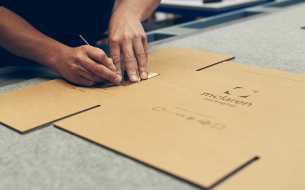 Worker cutting McLaren cardboard packaging